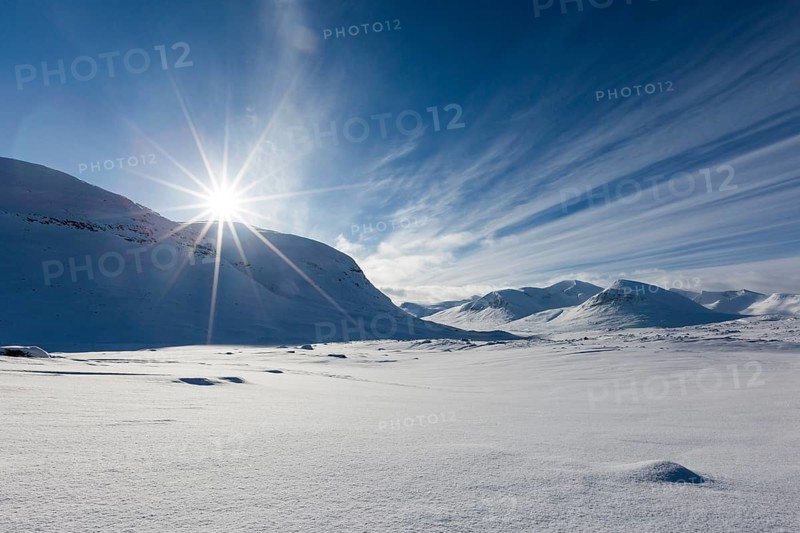 Sun over mountain range in the snow