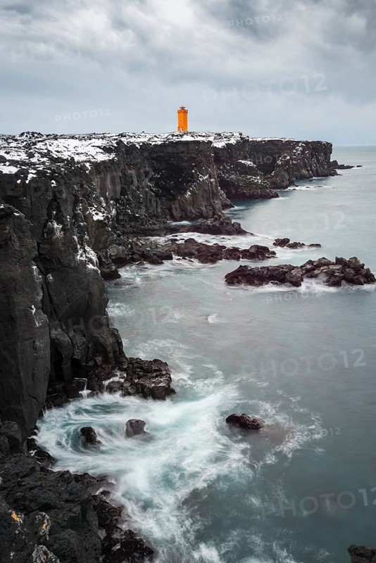 Orange lighthouse Ondverdarnes stands on a dark cliff