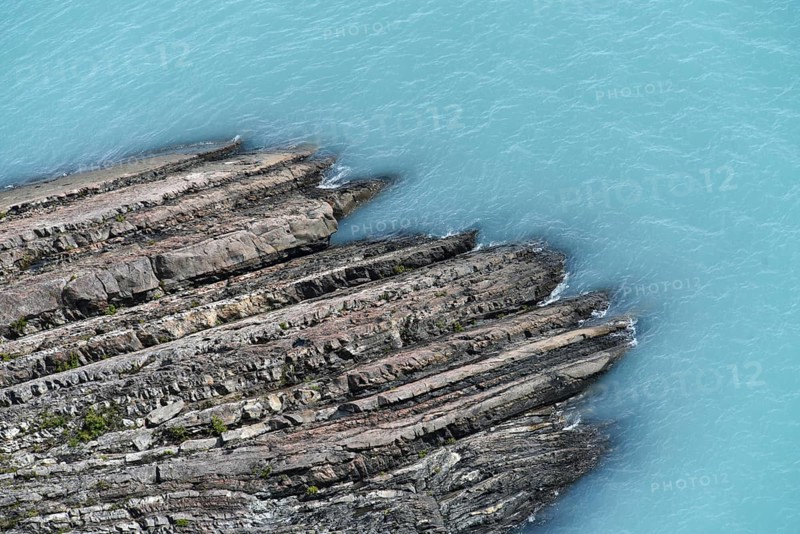 Glacial smooth-cut rock juts out into turquoise-blue Lake Argentino