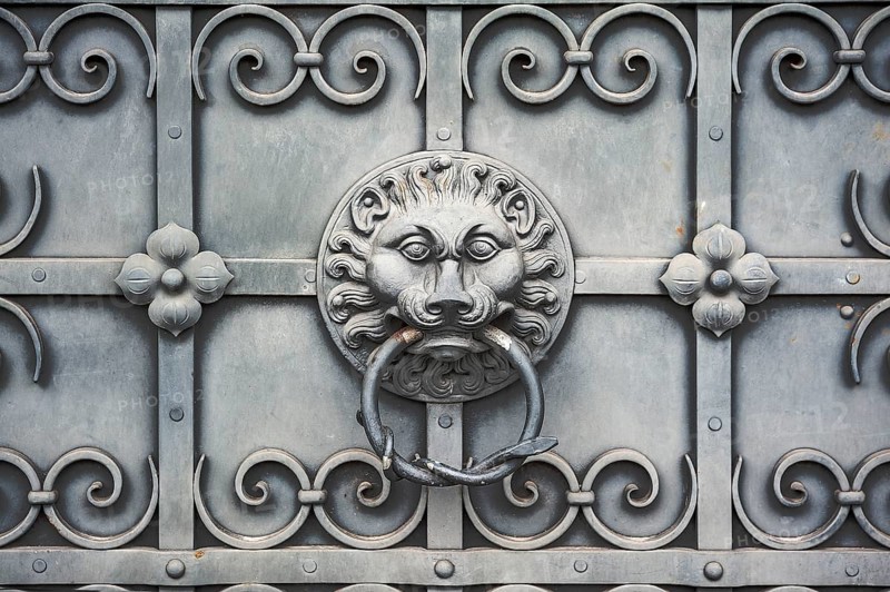Iron gate with lion's head as door knocker
