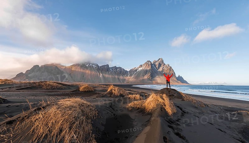 Man in red jacket stretches arms into the air