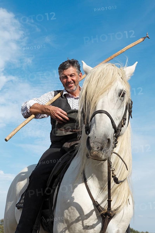 Gardian or traditional bull herder in typical working clothes on a Camargue horse