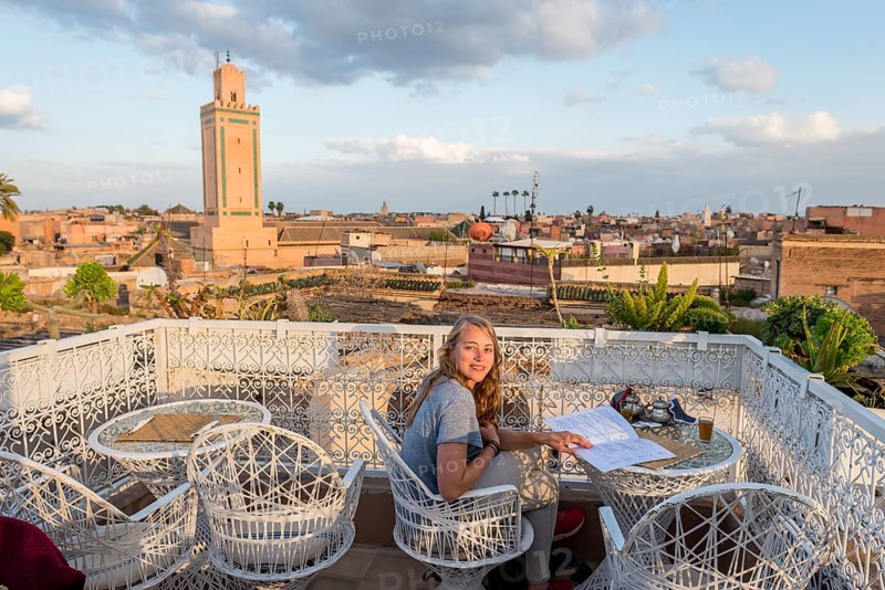 Young woman on a roof terrace reads the menu in the restaurant