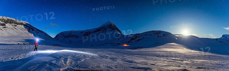 Person with tent on full moon in the snow