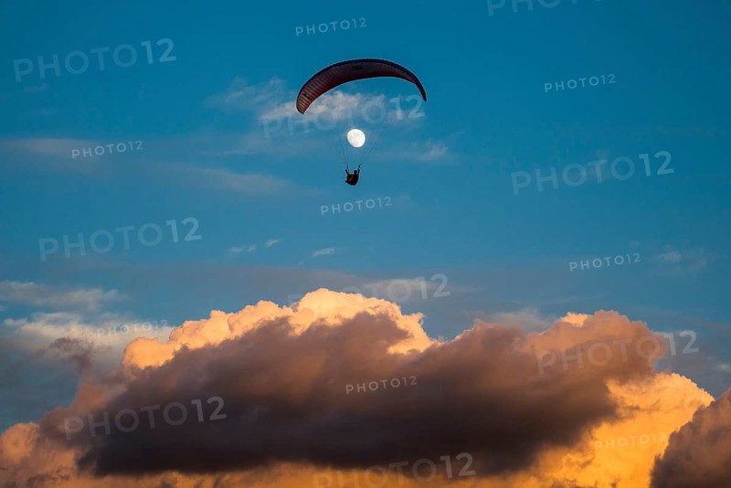 Paragliding in front of the moon above the clouds on the Canary Island of Tenerife
