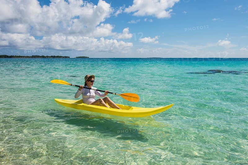Female tourist kayaking in the turquoise waters of Tikehau