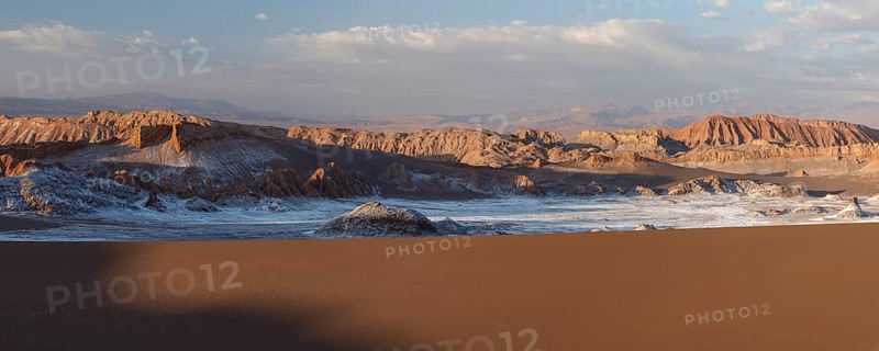 Giant dunes and bizarre red rock formations with white salt at sunset