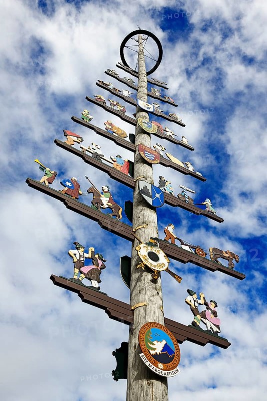 Maypole with guild sign in front of cloud sky