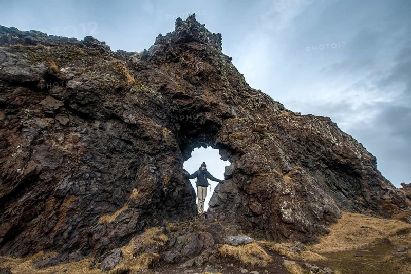Young man stands in rock arch
