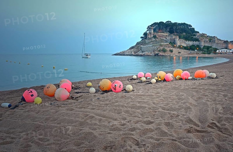 Orange and pink buoys on the sandy beach of Tossa de Mar