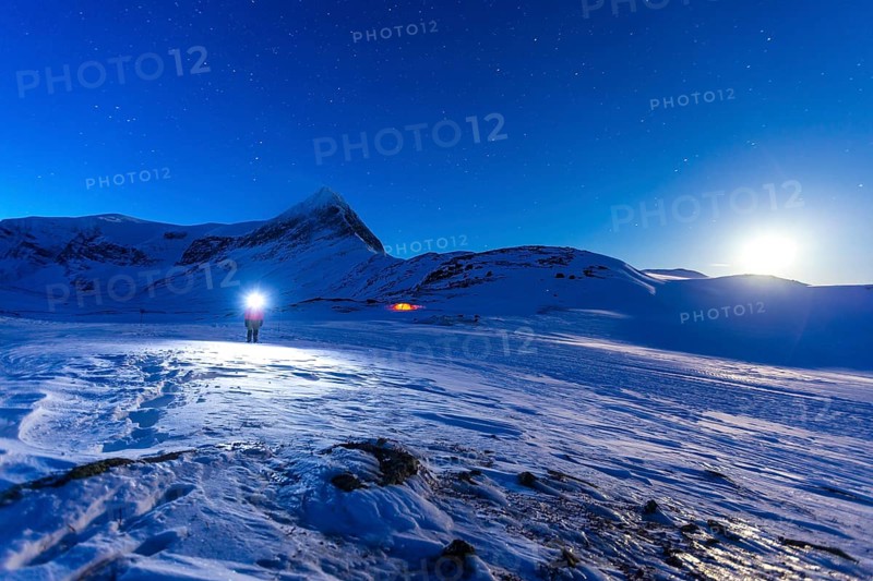 Person with tent on full moon in the snow