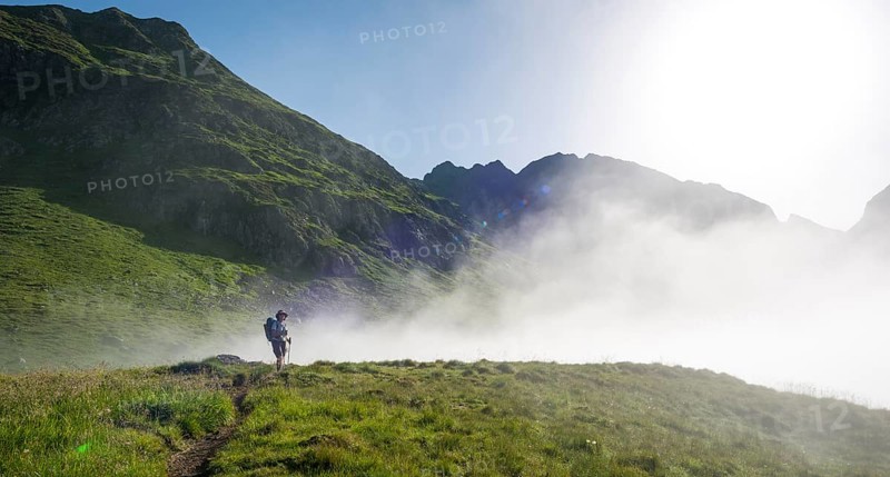 Hiker on the Schladminger Hohenweg with rising clouds of fog
