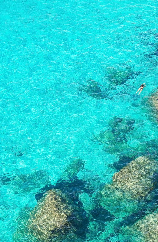 Person swimming in the emerald waters of Cala Mitjana