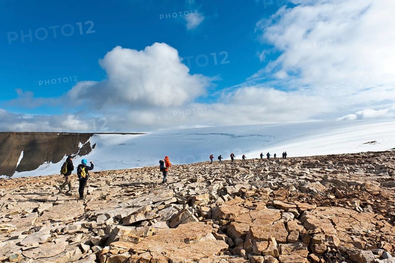 Hiking group in rocky terrain in front of Foxfonna glacier