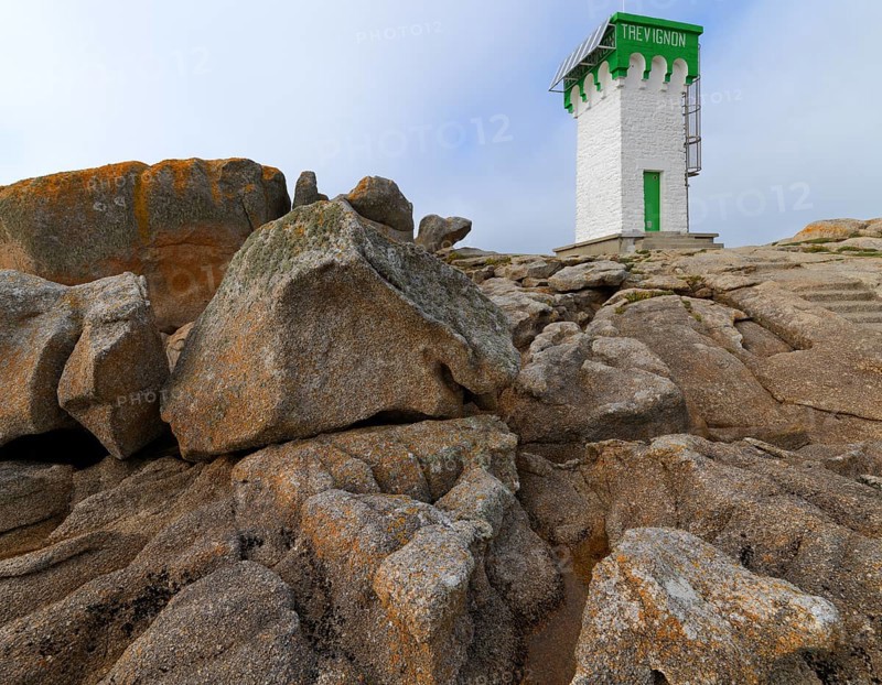 Green and white lighthouse on granite rocks