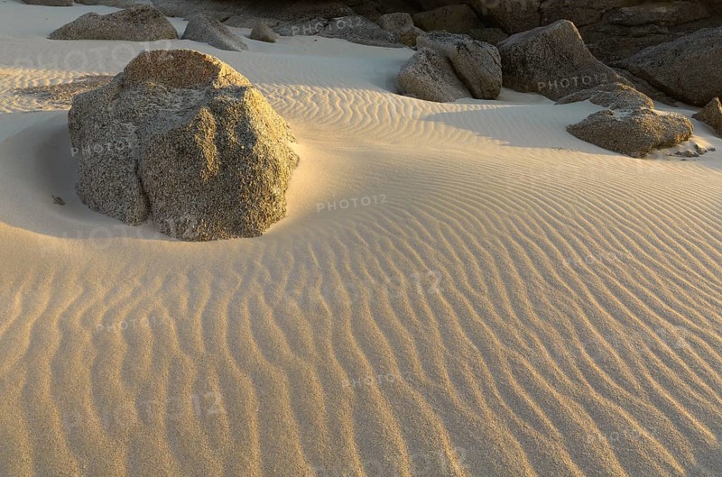 Granite rocks in the sand with wave structure