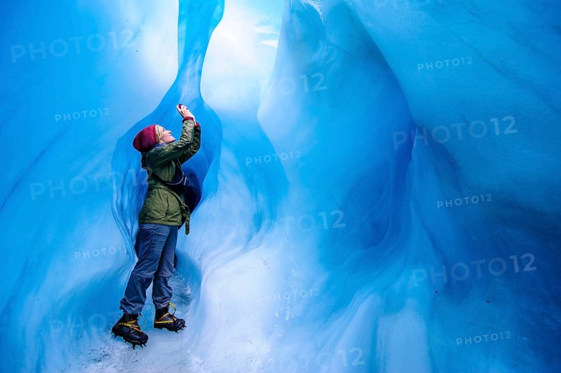 Woman photographing in a ice cave in Fox Glacier