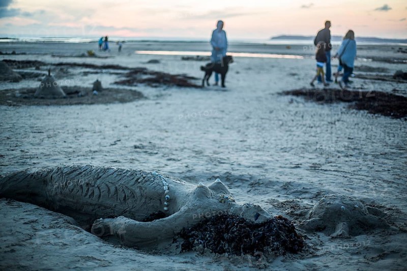 Mermaid of sand and strollers at dusk on the beach