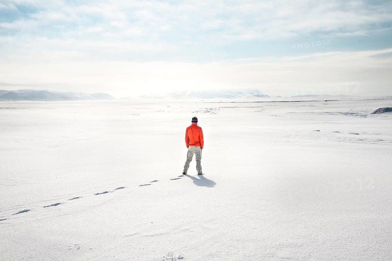 Young man stands alone in snowy landscape
