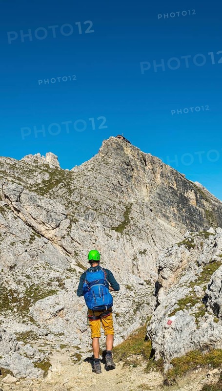 Hiker with climbing helmet on footpath to Nuvolau