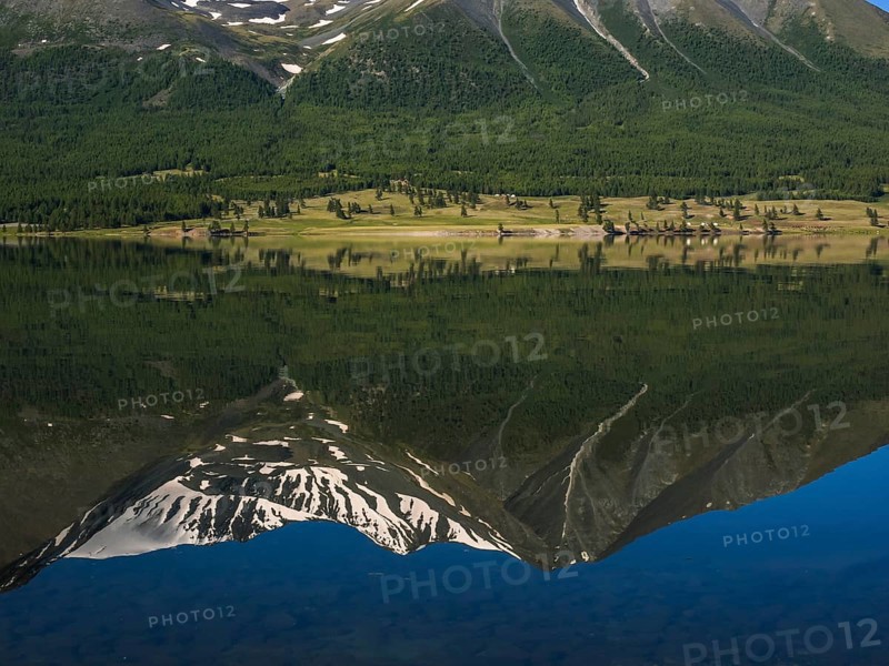 Khoton Lake with green forest landscape and water reflection of snow-covered mountains