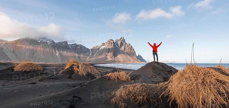 Man in red jacket stretches arms into the air