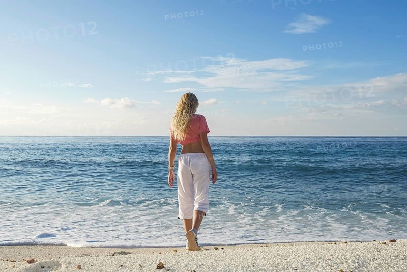 Young woman goes to the surf on a sandy beach