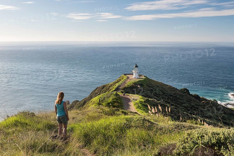 Woman stands in front of lighthouse at Cape Reinga