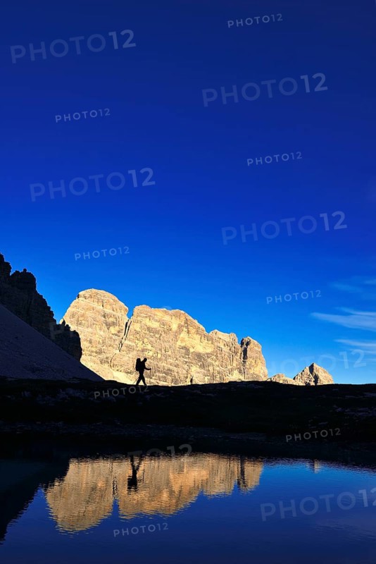 Hiker on the lake in the backlight