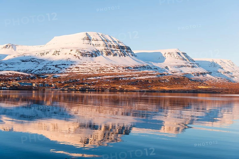 Water reflection of snow-covered mountains in a fjord