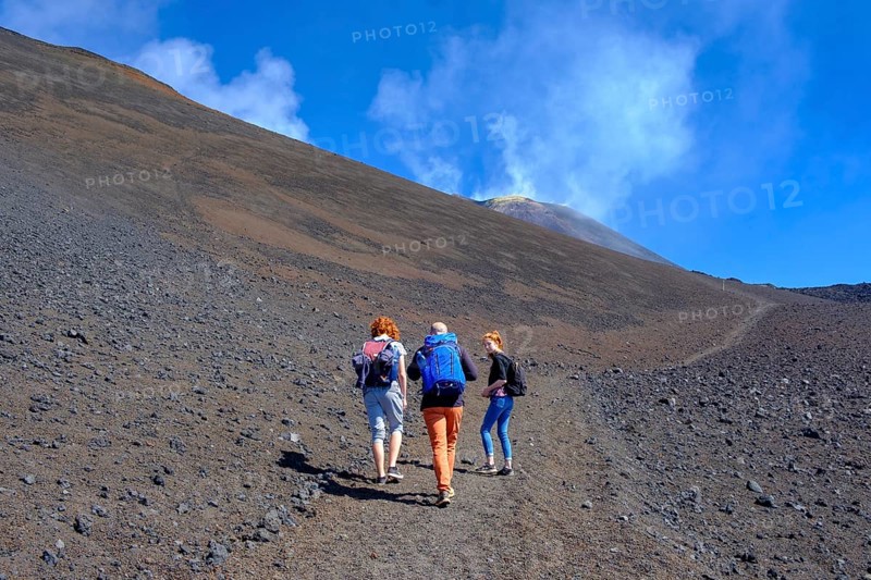 Hikers climbing through volcanic landscape