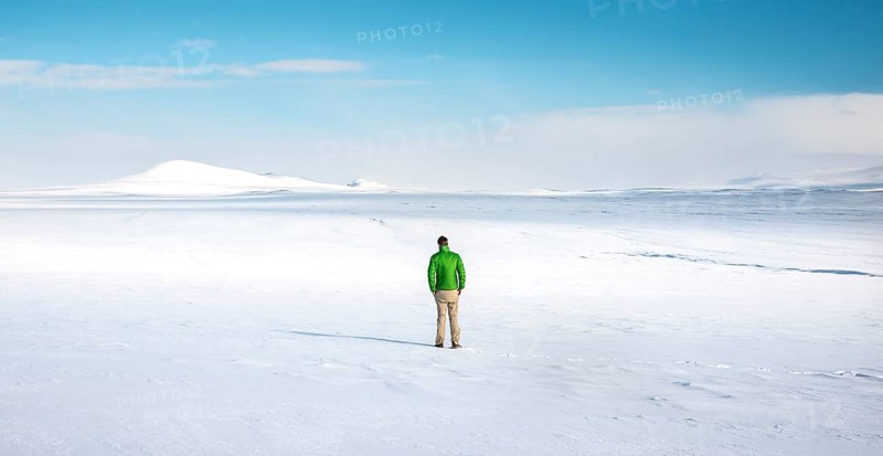 Young man stands alone in snowy landscape