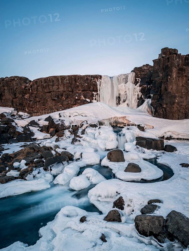 Partially frozen waterfall Oxararfoss in winter
