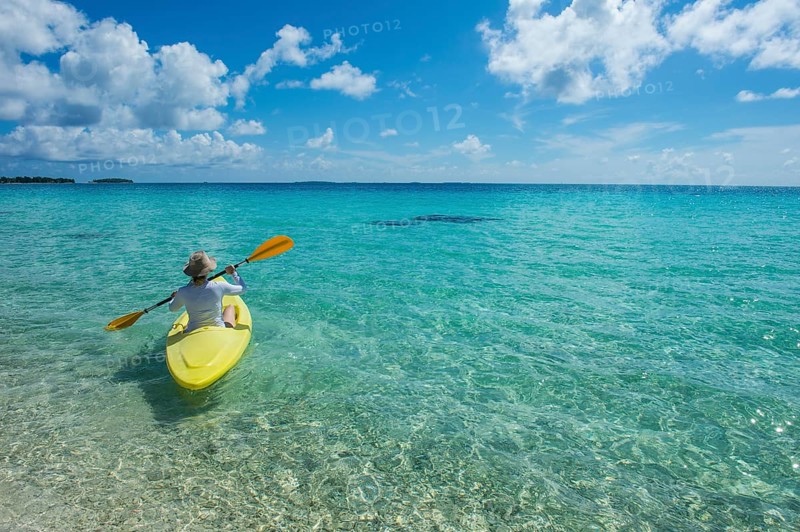 Female tourist kayaking in the turquoise waters of Tikehau