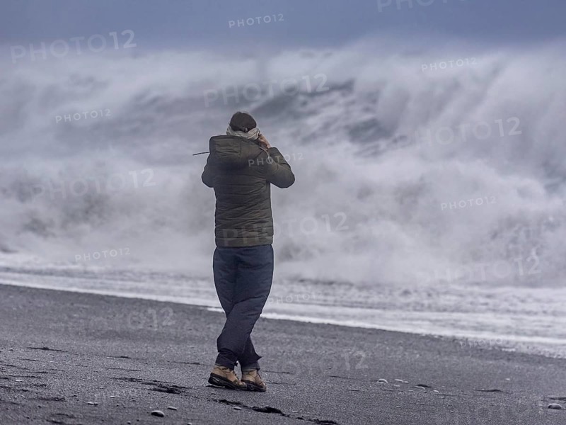 Tourist against storm waves at Reynisfjara Black Sand Beach