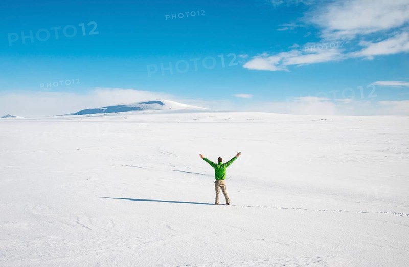Young man stands alone in snowy landscape