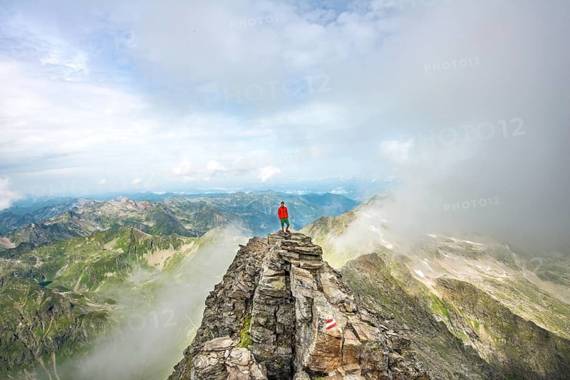 Hiker on the summit of the Hochgolling with rising fog