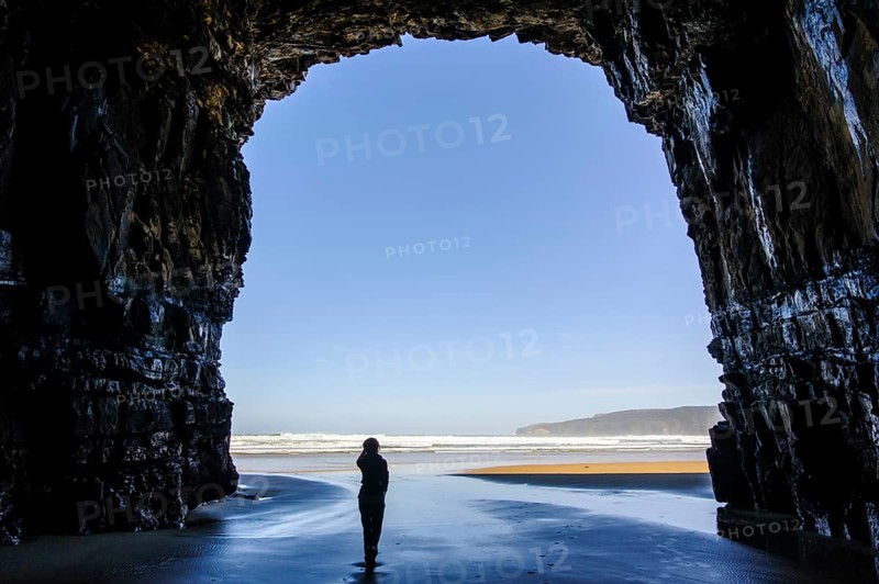 Woman standing in the giant entrance of Cathedral caves in backlit