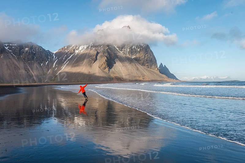 Man runs in a good mood on a black sandy beach