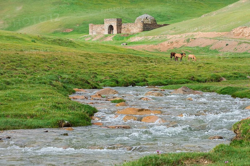 Tash Rabat with horses on meadow and mountain river