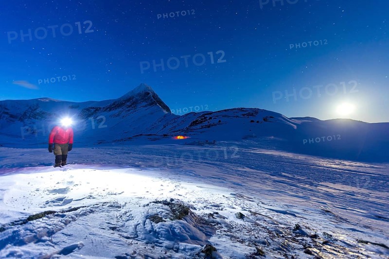 Person with tent on full moon in the snow