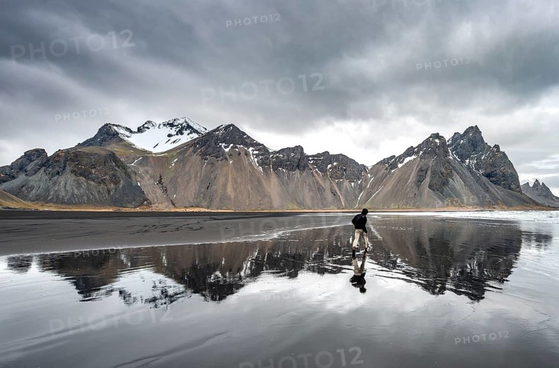 Hiker runs at the black sandy beach