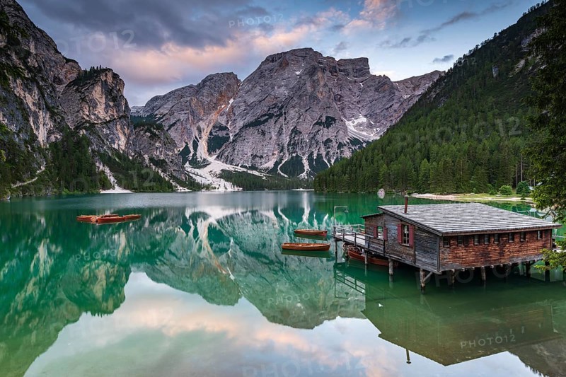 Green mountain lake with boats and boathouse