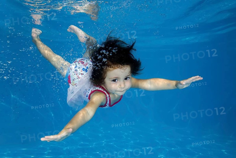 Little girl learns to swim underwater in the pool
