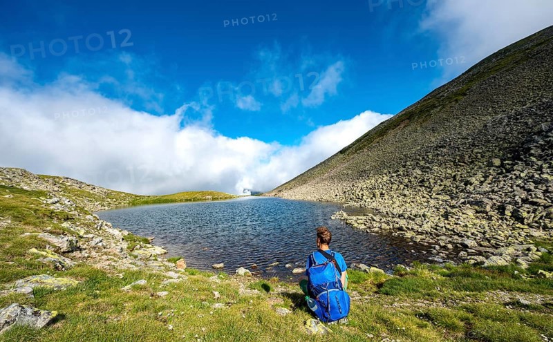 Hiker at the Sattelsee lake at the Greifenbergsattel