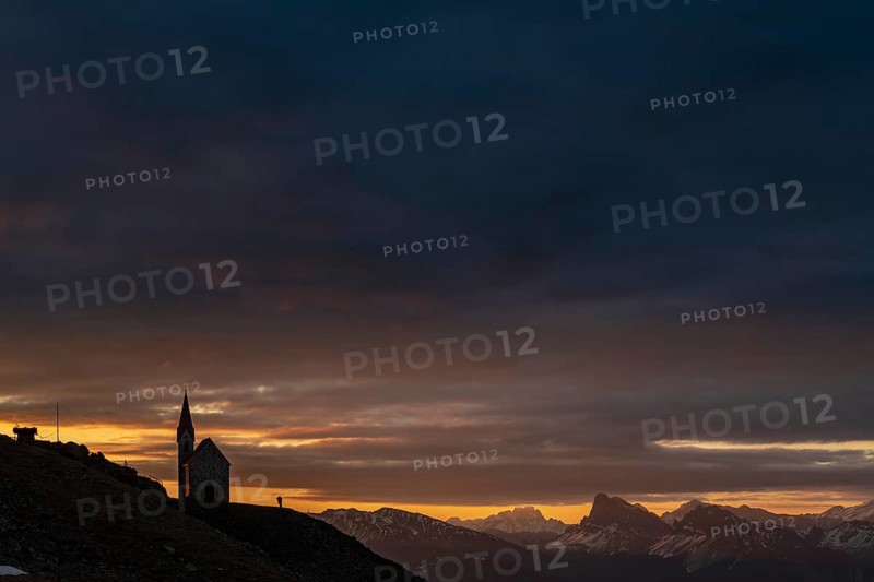 Latzfonser cross chapel at sunrise with dramatic clouds and South Tyrolean mountains