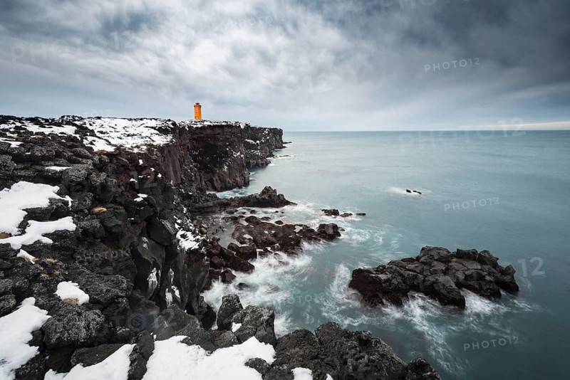 Orange lighthouse Ondverdarnes stands on a dark cliff
