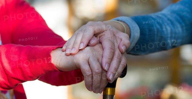 Girl puts her hand on the hands of an old woman with cane