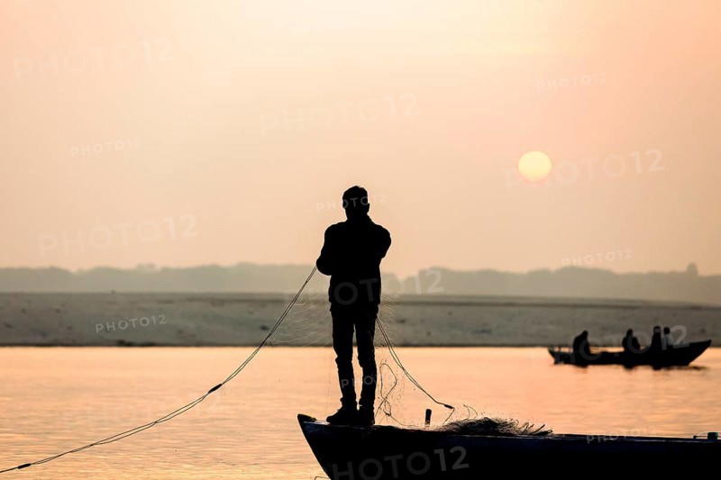 Fisherman throws net in the sunrise on Ganges river