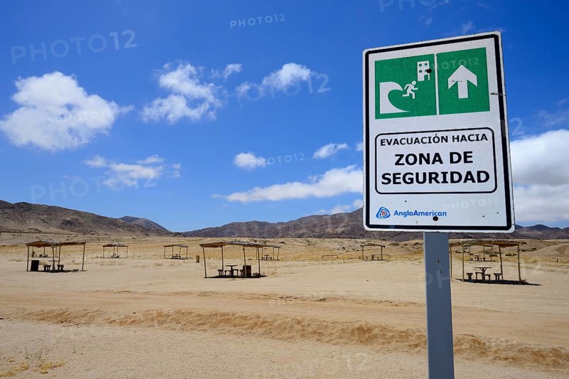 Tsunami warning sign near picnic area on the beach